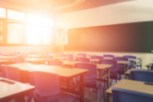 School classroom in blur background without young student; Blurry view of elementary class room no kid or teacher with chairs and tables in campus.